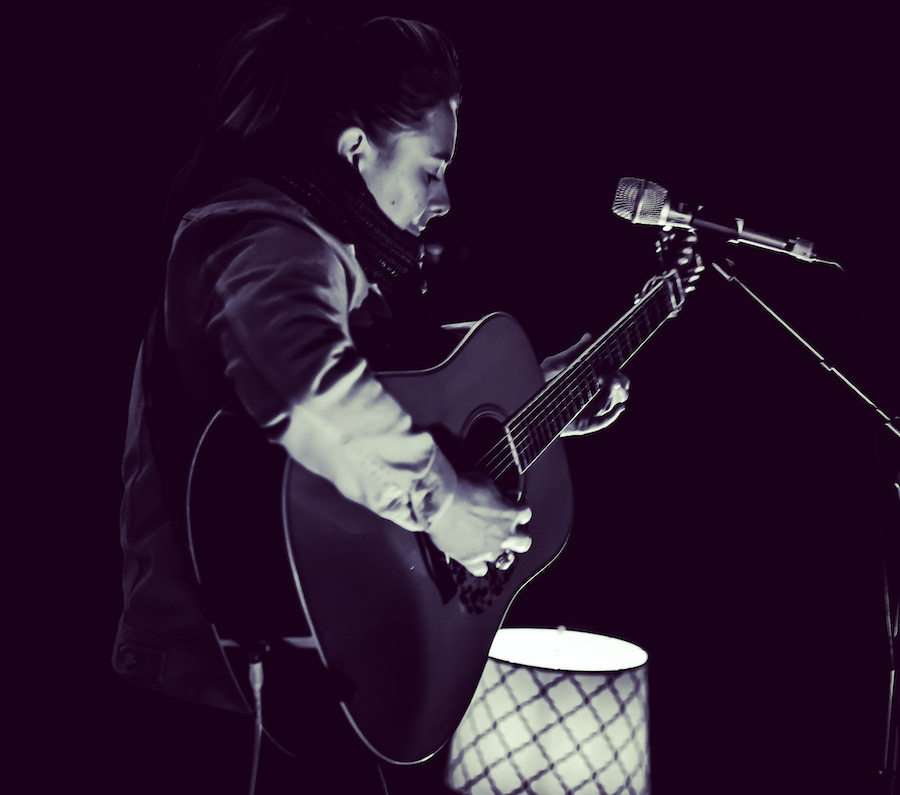 Sophia Johnson performing outdoors with her acoustic guitar